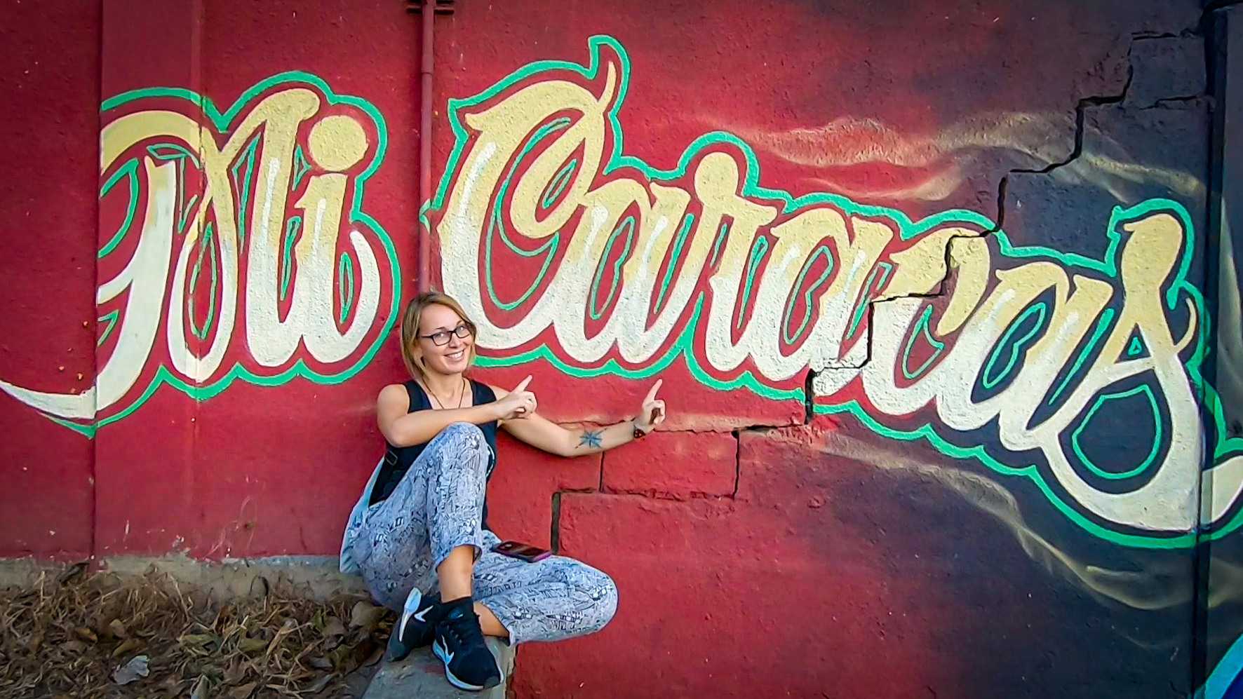 Zdjęcie przedstawia Adę Jarczyk na tle czerwonej ściany z żółtym napisem Mi Caracas.