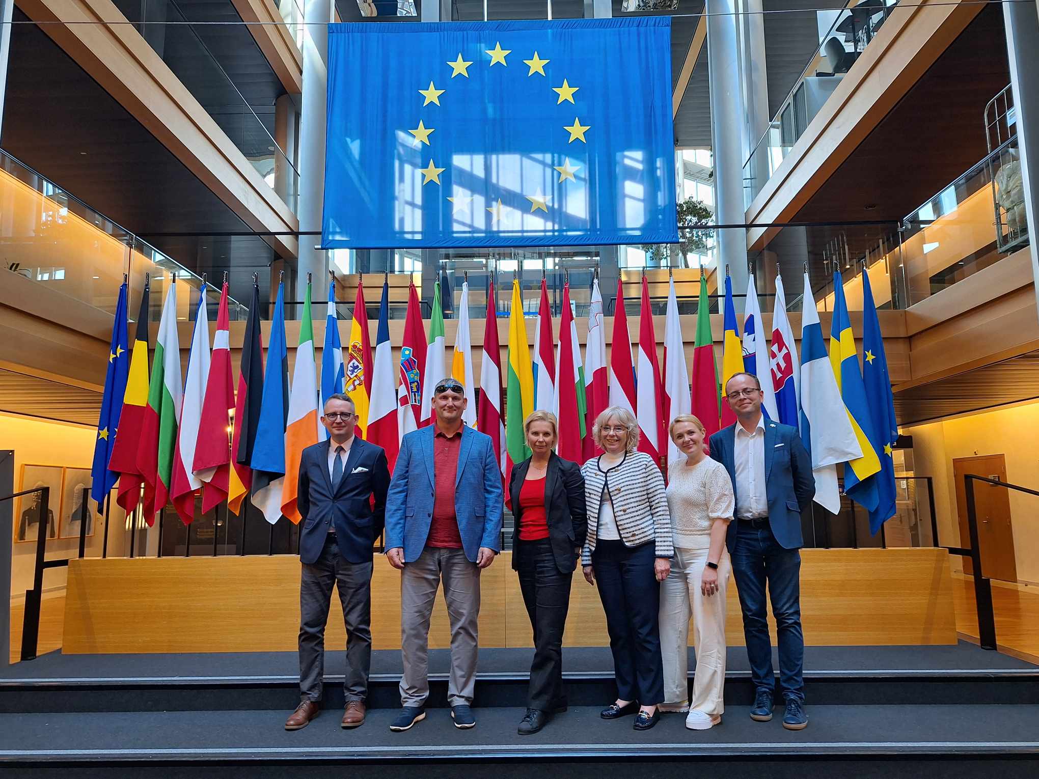 The photo shows the team members in front of the EU flag